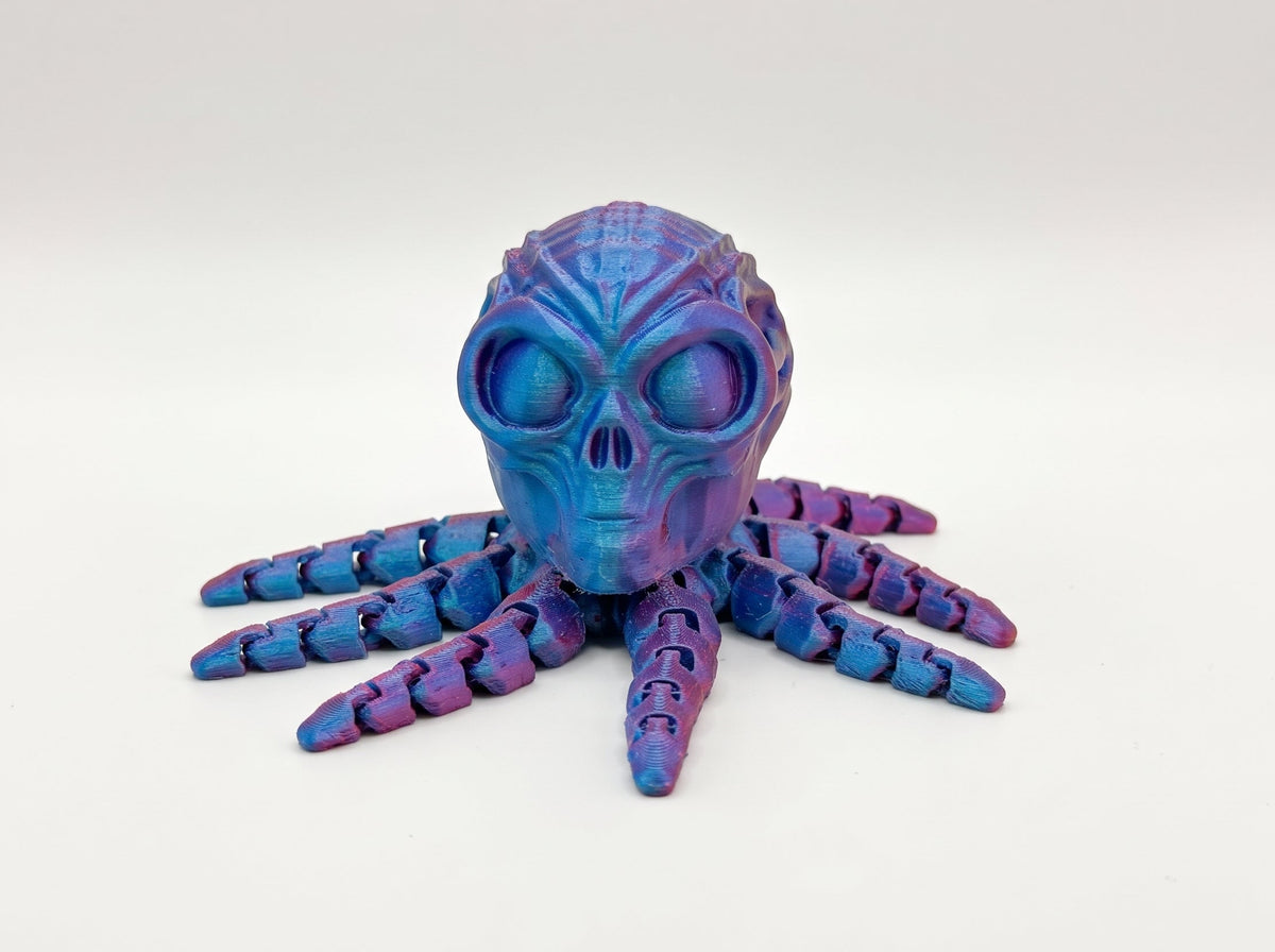Front view of a blue and purple articulated octo-alien with a skull-shaped head and segmented tentacles.