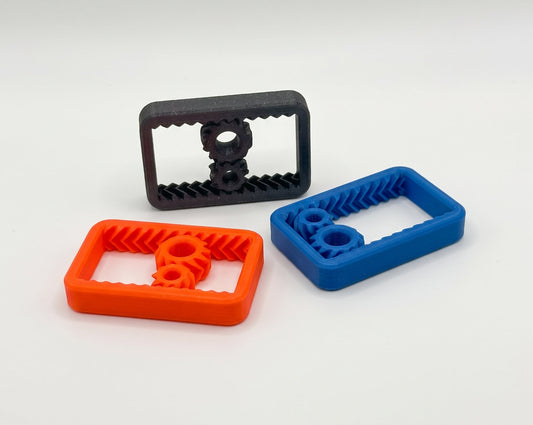 Gear rail fidgets in orange, blue, and black, each with two gears inside a rectangular toothed frame.