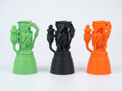 Green, black, and orange 3D-printed rocket engine models with detailed pipework and wide nozzles.