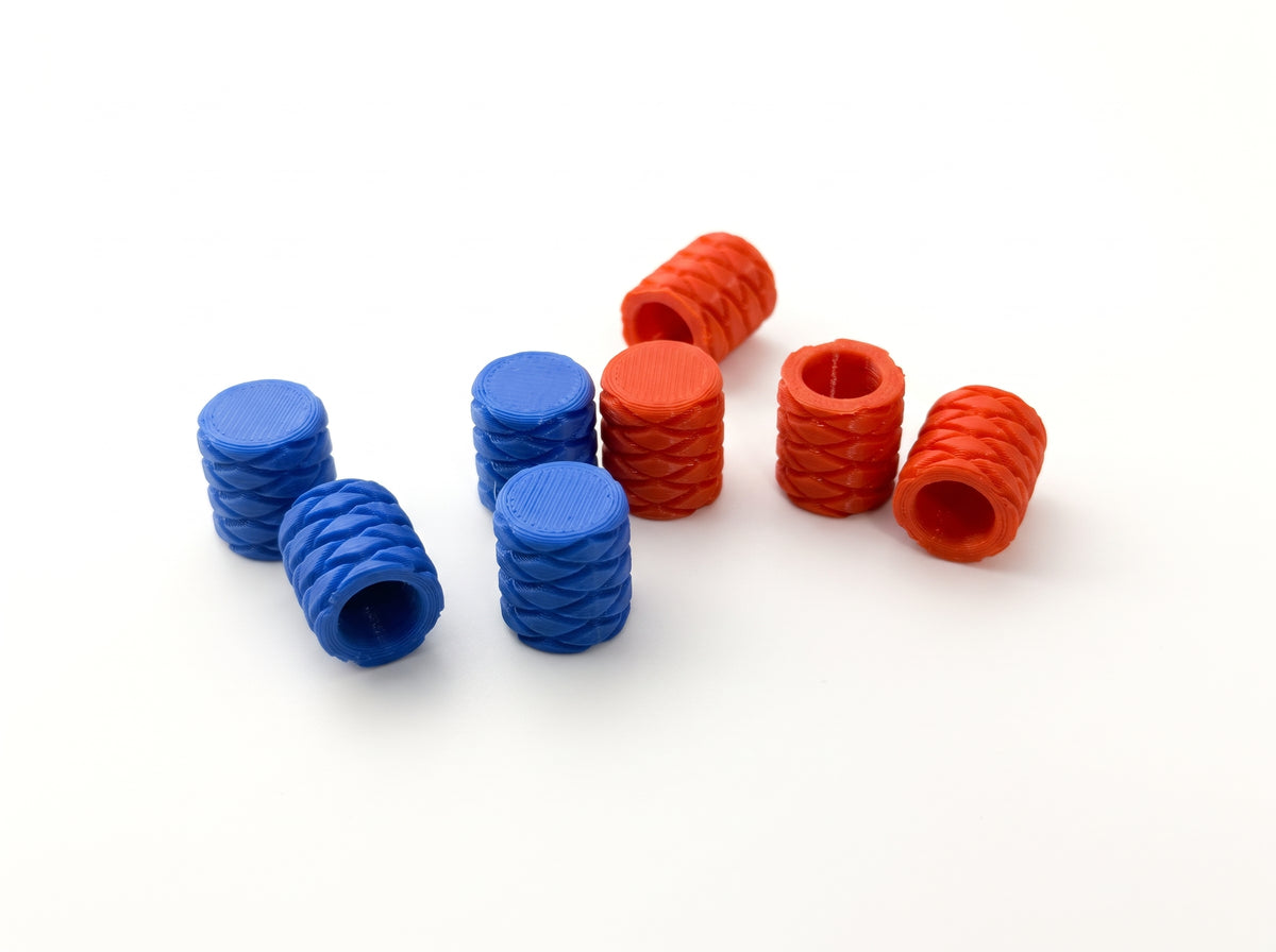 Blue and orange valve stem caps with raised textured sides and flat tops on a white background.